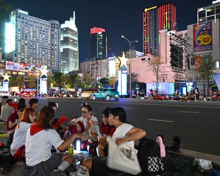 一群人坐在地上,身後是摩天大樓