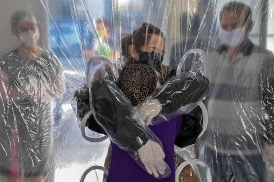 A hug through a plastic Covid safety curtain in São Paulo