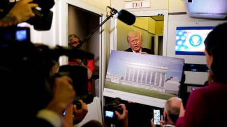Donald Trump, onboard Air Force One on Sunday, talks to members of the media while holding up renderings of the planned White House ballroom.