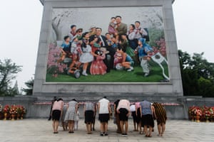 People bow before a giant mosaic image showing the late leaders, Kim Il-sung and Kim Jong-il, surrounded by happy citizens