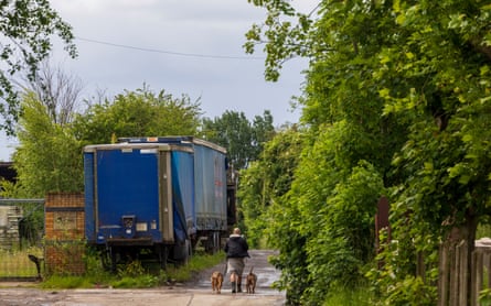 A man walks his dog past abandoned lorry trailers in the road leading to the site
