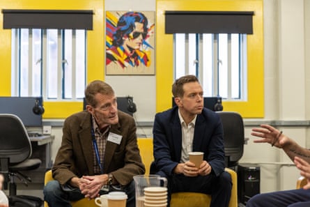 Two men sit listening to a conversation