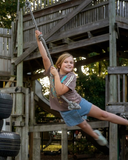 A young girl grins as she swings on a rope from a platform