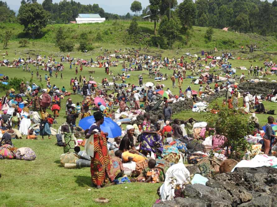 Un campo lleno de gente con sus pertenencias en fardos