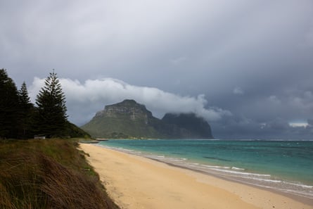 Sandy beach with mountains in the background under a stormy sky