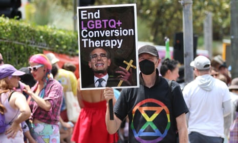 A protester at a rally on City Road, Sydney holds a sign saying 'End LGBTQ+ Conversion Therapy' with an image of the NSW Premier Dominic Perrottet holding a cross. 