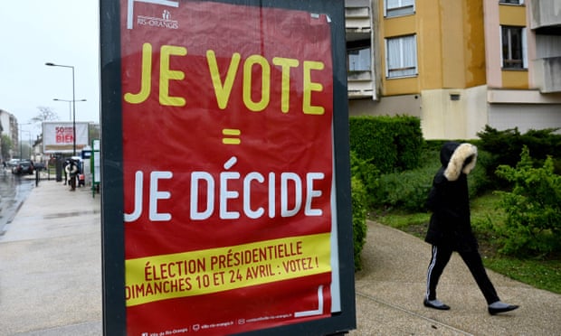 A pedestrian walks past a poster reading I vote = I decide