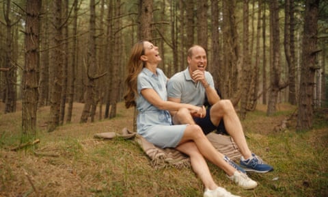 Princess of Wales with the Prince of Wales sitting on blanket on grassy mound with trees behind.