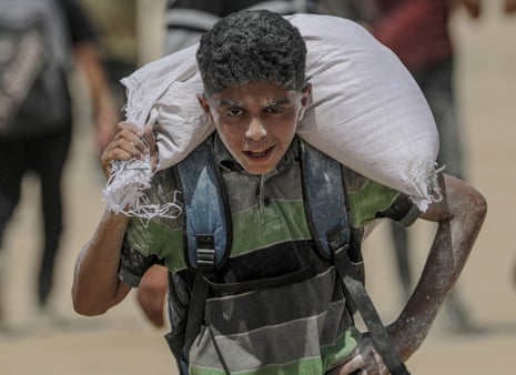 A Palestinian youth carry bag of flour near a food distribution point in Zikim, northern Gaza Strip, 08 August 2025.