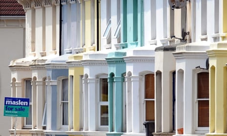 a for sale sign outside one of a line of pastel-coloured terraced houses in Brighton – cream, pale blue, yellow, peppermint green and white, seen in close-up view of their ground and first floors to form an abstract image