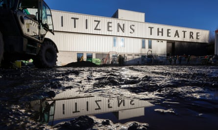 The name of the theatre reflected in a muddy puddle on the building site.