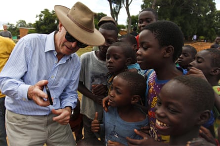 The former chief of the UK armed forces, General Lord Richards, shows a photograph to children in northern Zambia during a visit to the last battleground of WWI in Africa.