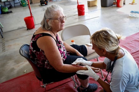 A woman is assisted by a first responder before being evacuated from Pine Island, Florida.