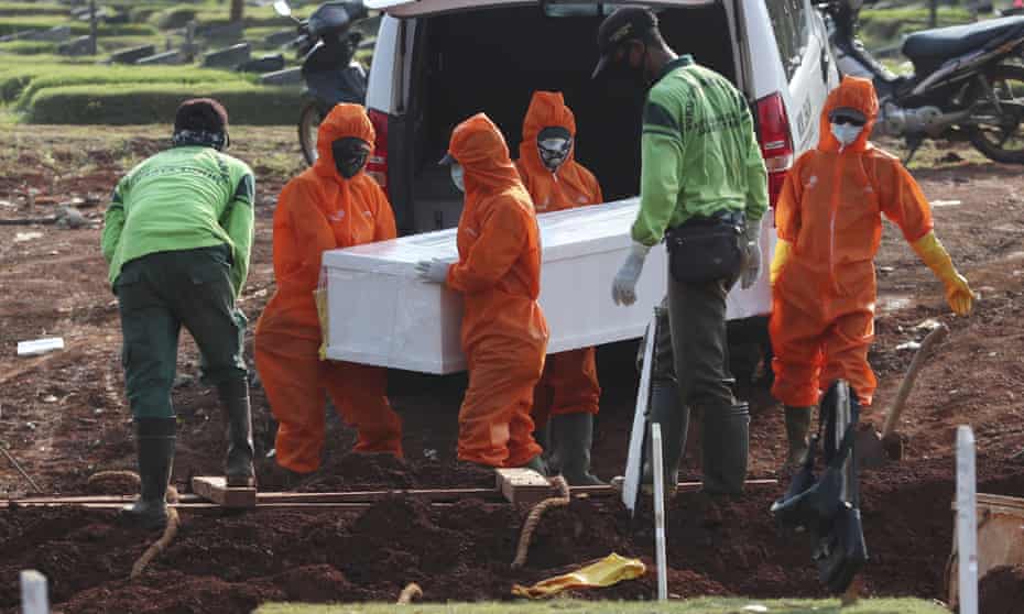 Workers in protective suits carry a coffin containing the body of someone who may have died of Covid-19 for burial at a special cemetery in Jakarta.