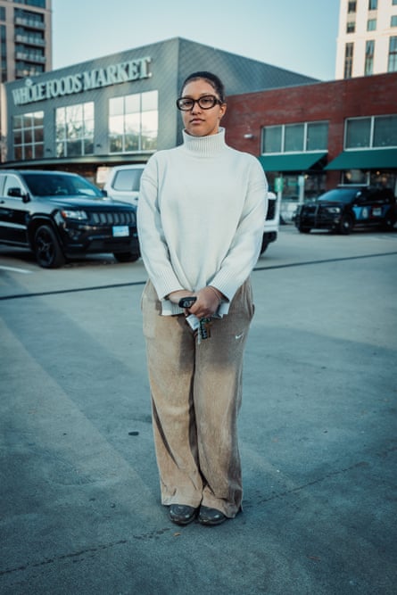 woman in white sweater holds her car keys as she stands in the parking lot outside a whole foods
