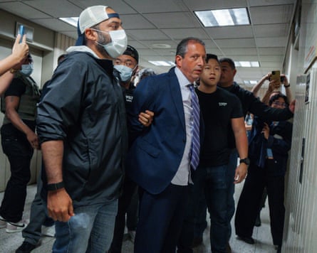 Man in suit with hands behind back being held by men in masks