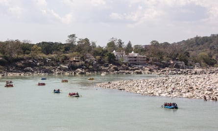 Rafts and dinghies on the Ganges. They pass an ashram coming from the rapids of the Ganges at Rishikesh, India.