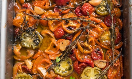 A tray of different coloured roast tomatoes with herb sprigs on top