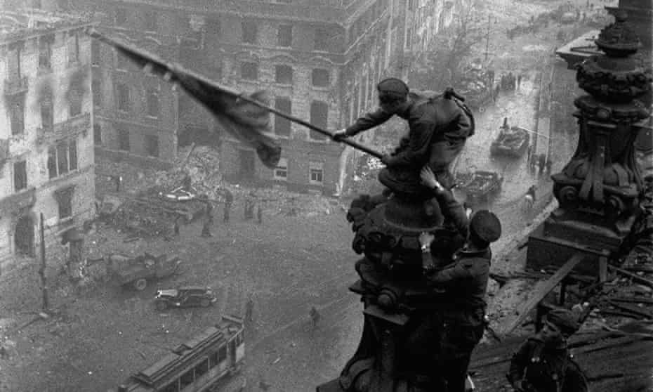 Soviet soldiers hoist the red flag over the Reichstag in May 1945. The Red Army committed mass rapes on the road to Berlin.