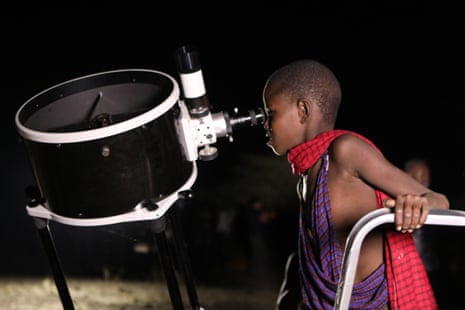 A Kenyan young boy looks through a telescope as the moon turns red in Oloika.