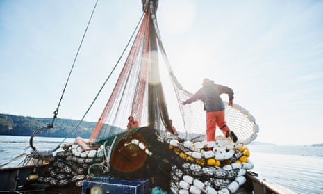 Crew member organises net as a purse seine fishing boat sets out looking for salmon.