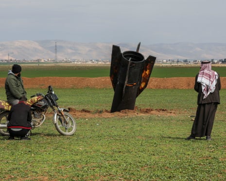 People stand next to an Iranian missile after it fell near Qamishli international airport in Syria