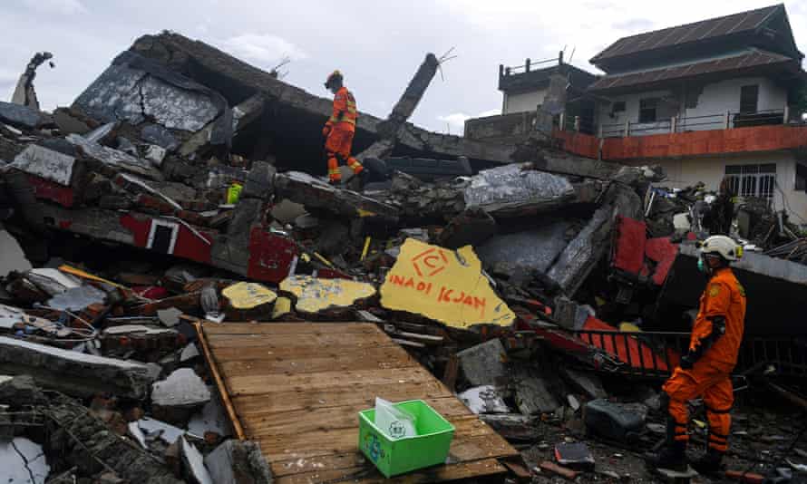 Indonesia earthquake rescuers hampered by damaged infrastructure after dozens killed | Indonesia 1 Search and rescue personnel inspect a collapsed building in Mamuju on Saturday.
