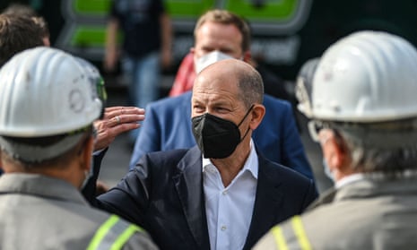 A masked Olaf Scholz talks to employees in safety gear
