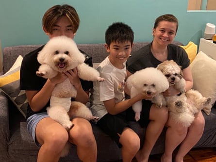 Trois personnes assises sur le canapé, chacune tenant un petit chien blanc