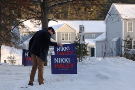 a man puts a sign for nikki haley out in the snow in front of some houses