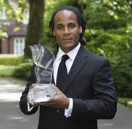 Michael Thomas in suit and tie holding a glass sculpture representing the Dublin literary prize