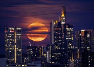 The moon rises behind buildings in the banking district in Frankfurt, Germany