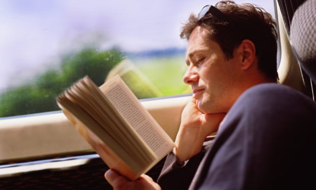Man reading paperback book on train