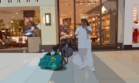 A Filipina worker talks on a phone while pushing a child in a buggy through a shopping centre