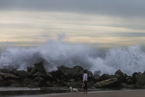 A man photographs the big waves in the breakwater in Venice beach in Los Angeles, California