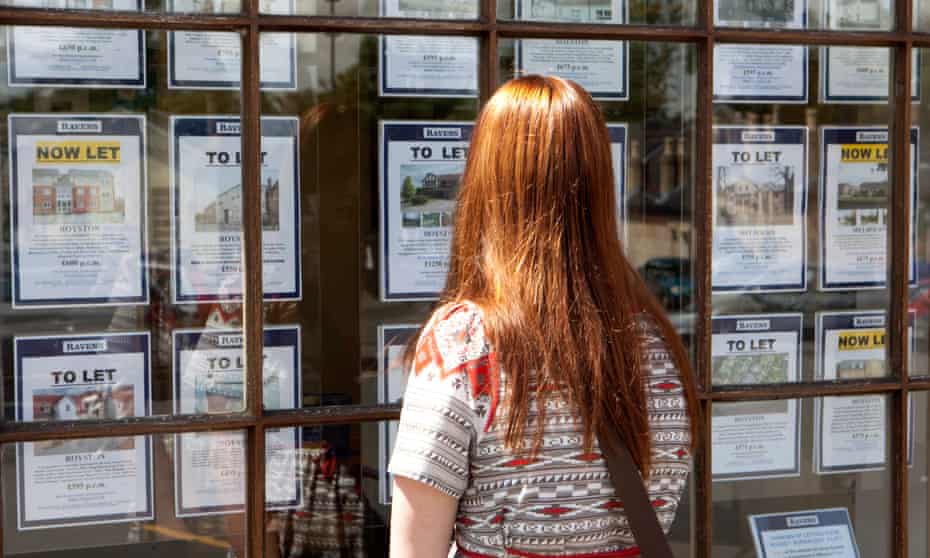 A young woman looks into the window of an estate agent.