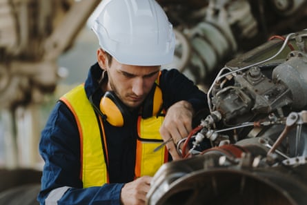 Mechanics inspect the engines of a large plane before takeoff at a summer airport. (PHOTO)Mechanics inspect the engines of a large plane before takeoff at a summer airport. (PHOTO)