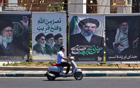 A man on a scooter rides past banners of Iran’s late supreme leader Ayatollah Ali Khamenei and his son and successor Ayatollah Mojataba Khamenei, that have been hung up around Sadeghiyeh Square in Tehran
