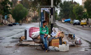 A boy waits to load his family’s belongings on to a bus in Palmyra, Syria.