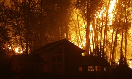 A wildfire burns behind a home in Twisp, Washington, in August 2015.