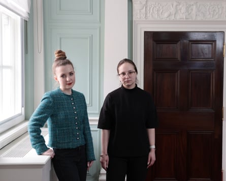 Ilona Khmeleva and Olena Yurchenko stand by a window looking at the camera