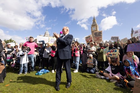 Ed Davey addresses parents and children on the green outside Westminster; mothers, fathers and kids hold up signs with messages including 'make sure my voice is heard', 'don't take away EHCPs from speech and language needs' and 'I want to be included not excluded'.