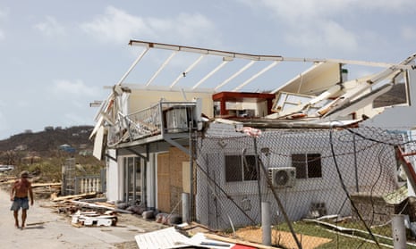 White building with destroyed roof as man walks past