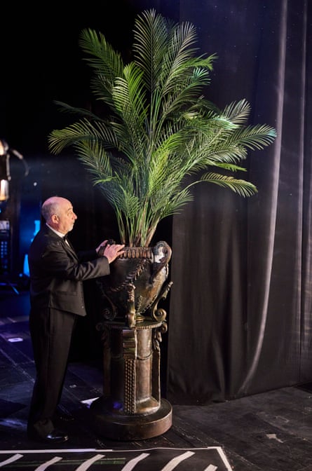 Behind the scenes, a palm is wheeled on, part of the hotel set.