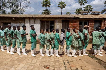 Health workers wearing green scrubs queuing for food in the courtyard of a hospital