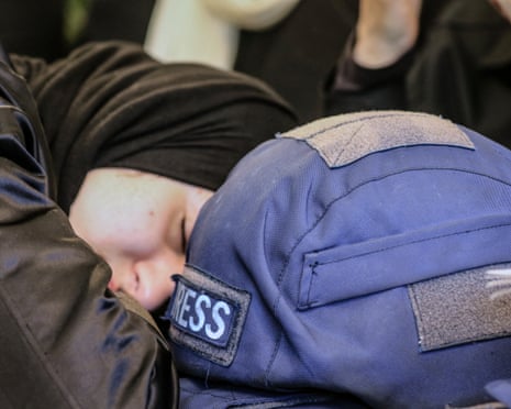 A woman mourns next to a press ballistic helmet as relatives and friends gather at the house of Amal Khalil.