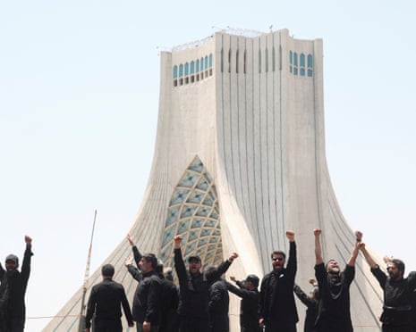 Men wearing black raise their fists in front of a building in Tehran