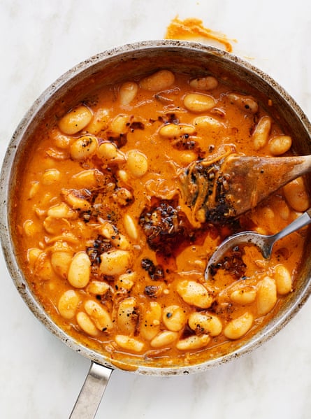 A silver pan with bean in an orange creamy sauce