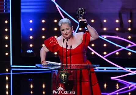 Siobhán McSweeney raises her BAFTA trophy triumphantly at the podium on stage