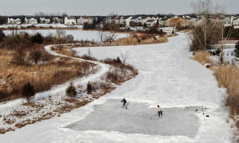 Two men practice their hockey skills on a pond after clearing an area of snow in Round Lake Heights, Illinois. More frigid weather is forecast.